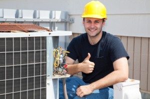 Contractor Kneeling Next To Outdoor Hvac Unit, Smiling At Camera And Giving A Thumbs Up While Wearing A Yellow Hardhat.